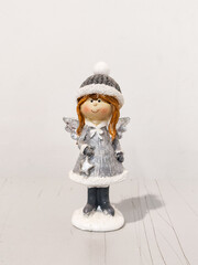 A silver angel statue with a hat and a bow on her dress