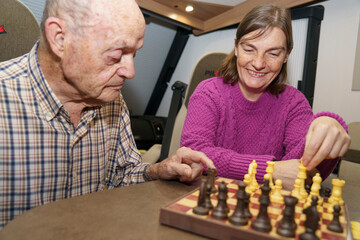 Senior man and caregiver woman playing chess in a camper van