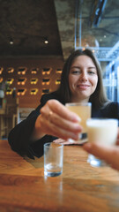 A woman clinks glasses and drinks an alcoholic tincture - close-up