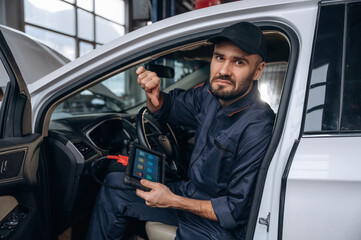 Dislike, thumb down. Mechanic working in a car service station