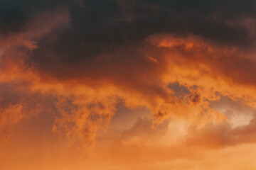 Moody storm clouds illuminated by vibrant sunset light—an inspiring backdrop for artistic or...