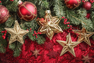 Festive gold stars with red baubles on pine branches view.