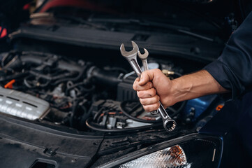 Tools in hand. Close up view of mechanic in car service station