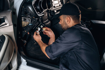 Electronics under the steering wheel. Mechanic working in a car service station