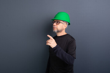 Portrait of a civil worker wearing a green helmet and black clothes, posing for the photo and...