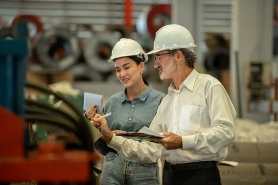 Two professional technician engineer worker use clipboard checking operating equipment machine monitors and check Production process machinery. Two engineer confederate control factory machine