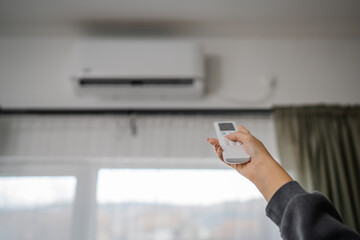 Woman hold a remote control with air conditioner in the living room
