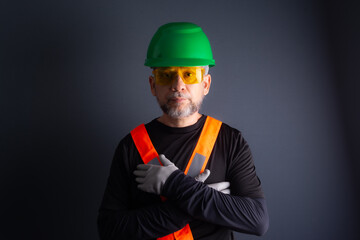Photo of a civil worker wearing a green helmet, reflective vest and protective glasses. isolated on gray background.