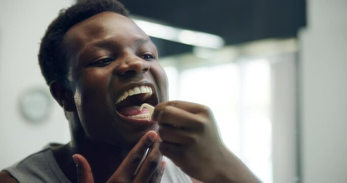 Bathroom, hygiene and flossing of teeth, man and cleaning of mouth for dental care, flosser and home. Morning, grooming and black person with tools for oral health and prevention of tooth decay