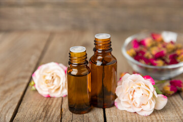 Rose essential oil on a textured background.Roses and a bottle of rose perfumed water.Aromatherapy treatment. Beauty concept. Spa procedure.Natural organic oil.Anti-stress,detox relax.Place for text