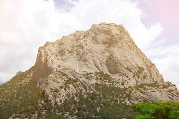 Majestic rock formation under a partly cloudy sky, showcasing rugged terrain and sparse vegetation, perfect for nature and adventure themes