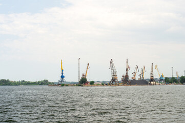 Panoramic view of a busy harbor with numerous cranes and cargo piles, highlighting the industrial landscape and logistics operations at a river port