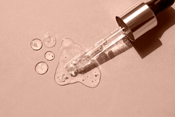 Serum drops and a pipette on a beige background. Top view. Color of the Year Mocha Mousse.