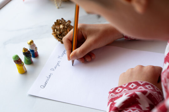 Ni&ntilde;o escribiendo la carta a los reyes magos con adornos navide&ntilde;os al fondo. Queridos Reyes Magos. 6 de junio