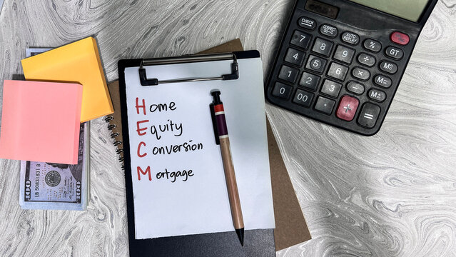 Concept of HECM - Home Equity Conversion Mortgage write on paperwork isolated on Wooden Table.
