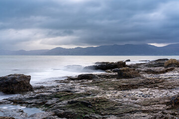 Rocky coast of the sea with storm clouds above distant mountains