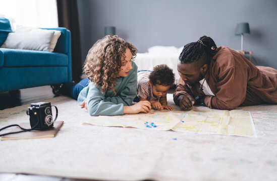 Diverse family engaged in interactive map reading session, Child and parents collaborating on route planning using colorful markers to highlight destinations during weekend leisure at home interior
