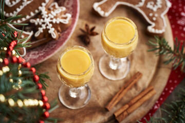 Two glasses of Eiercognac with homemade gingerbread Christmas cookies, spices and spruce tree branches