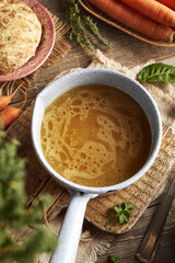Chicken bone broth in a saucepan with fresh vegetables