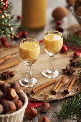 Two shot glasses of Eiercognac with spices, hazelnuts and Christmas decoration