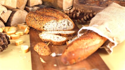 Rustic artisan bread with seeded crust rests on wooden board, surrounded by pinecones and warm natural textures, evoking cozy and homely ambiance perfect for seasonal gatherings.