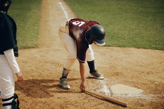 Baseball player preparing to bat at home base on a sunny day