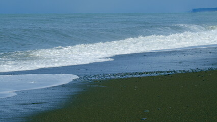 Stone Beach Of Small Pebbles Washed By Small Foamy Waves. Clear Water By The Sea. Still.