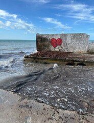 Concrete breakwater on the beach with a red heart painted on it