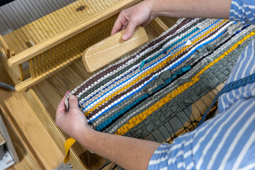A close-up view of a weaving loom in action, crafting upcycled fabric from textile scraps and...