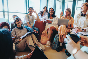 Diverse group of students enjoying a casual classroom setting with technology and study materials