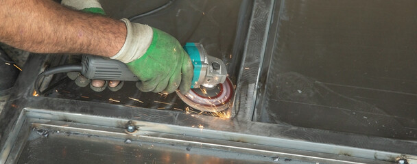  Worker using angle grinder. Cutting detail of iron gate