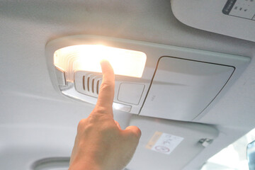 The index finger extends and presses the light on-off button.  Ceiling inside the car.