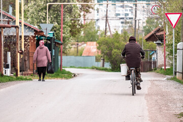 A woman is walking down a street with a man riding a bicycle