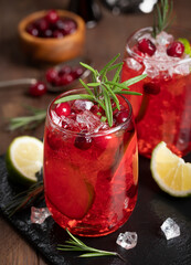 Cranberry cocktail with lime and ice garnished with rosemary
