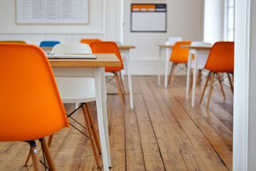 Brightly colored chairs in modern classroom setting create an inviting atmosphere for learning. wooden floor and minimalist design enhance spaces functionality and style
