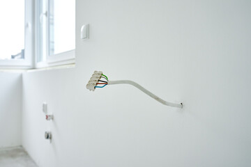 Close-up of electrical wires extending from white wall. Electrical work during apartment renovation. Electricity cable in new apartment