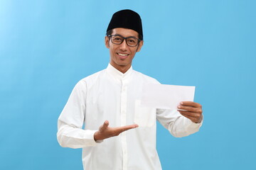 Asian muslim man holding envelope filled with money. Give THR or donation or Zakat Fitrah as an...