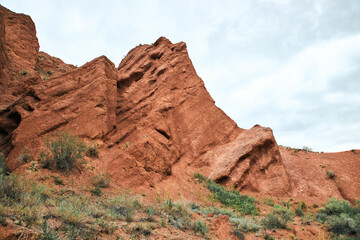Fototapeta premium Travel destination Konorchek canyon, sheer cliffs subject to erosion, famous landmark Kyrgyzstan, Central Asia. Rock formation, natural landscape, hiking trekking area, sandstone red rocks