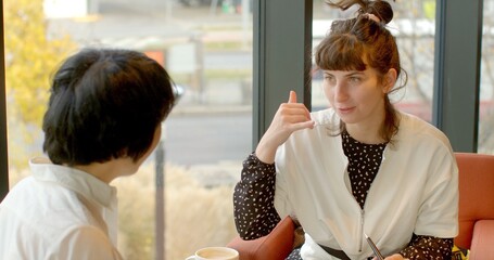 A woman uses a hand gesture to mimic holding a phone, signaling the intention to make a call. Her expressive movement captures a clear and relatable form of non-verbal communication.