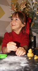 little girl makes xmas coockies with xmas decorations on the background