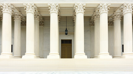 Obraz premium A wide-angle view of a courthouse exterior showcasing its grand entrance with columns and steps, illuminated by natural light casting intricate shadows. The architectural details and symmetry 