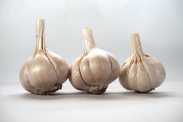 Close-up of three garlic bulbs neatly arranged in a row against a plain white background.