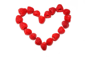 Ripe juicy raspberries laid out in the shape of a heart isolated on white 