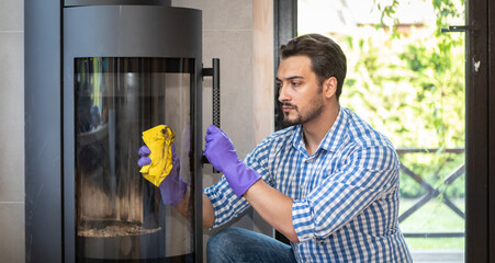 A young man cleans a fireplace to be prepared for the harsh winter during an energy crisis	