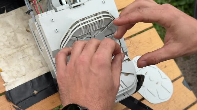 Skilled Technician Installing FTTH Equipment: Fiber Optic Cables, Splitters, and Cabinets for Home Connectivity
