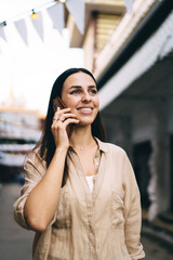 Caucasian woman with cute smile on face happy with received international call conversation using roaming in city, cheerful hipster girl using 4g wireless for calling via smartphone application