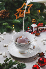 Milk is poured into a mug with a chocolate bomb. Dessert filled with hot milk.