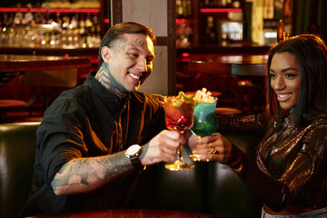 A young couple shares cheerful moments over colorful drinks while enjoying a night out.