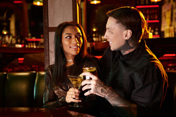 A young couple laughs and enjoys drinks together at an indoor bar, creating sweet memories.