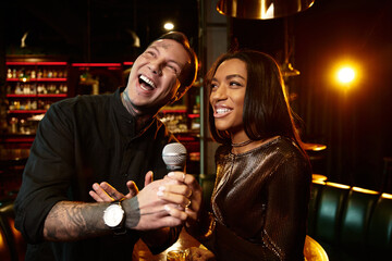 A young couple shares laughter while enjoying a fun evening at a lively bar.